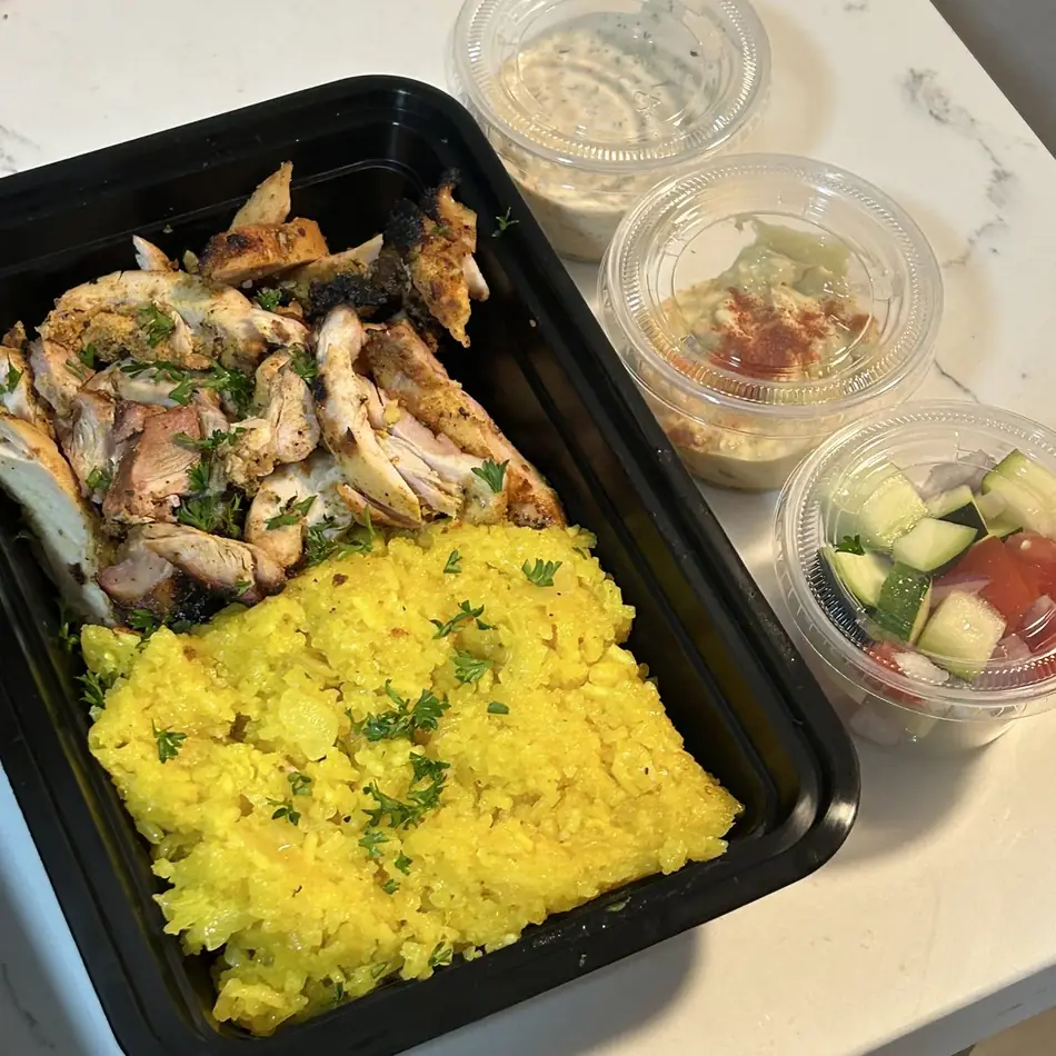 Chicken shawarma over turmeric rice with tzatziki, hummus and cucumber tomato salad